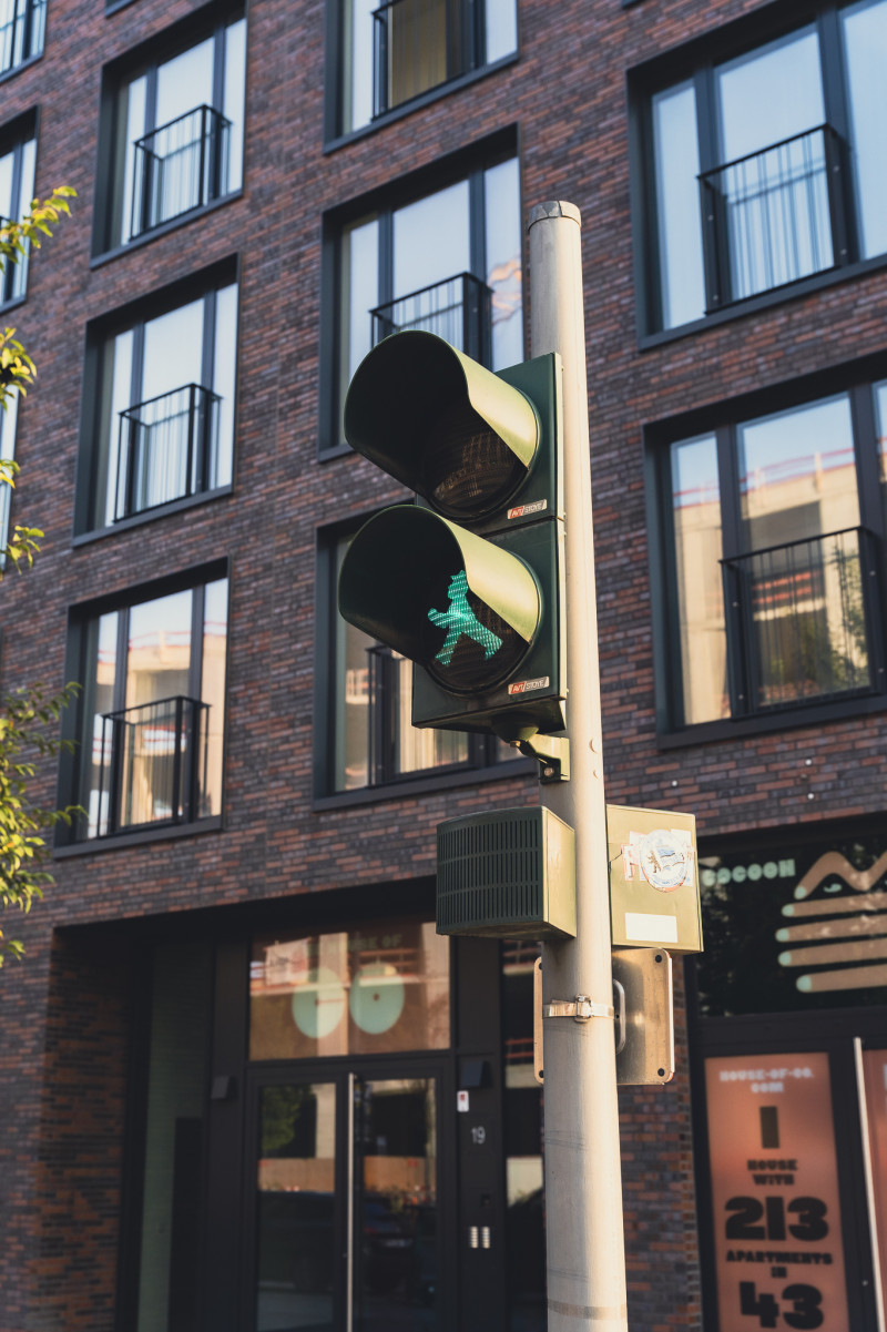 Eine Ampel mit einem grünen Ampelmännchen vor einem Backsteingebäude