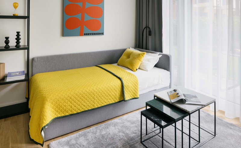 Coliving Wohnung in Berlin mit Blick auf gemütliche Schlafcouch mit gelber Decke