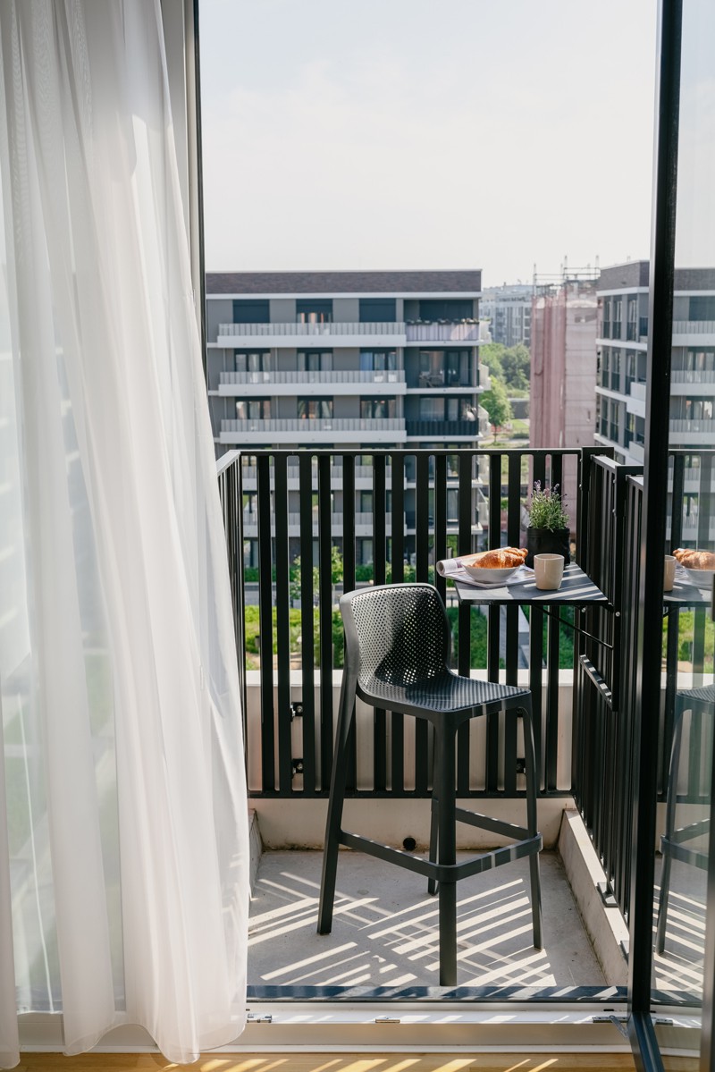 Kleiner Balkon unserer Mikroapartments mit Tisch, Stuhl und Aussicht in den Innenhof