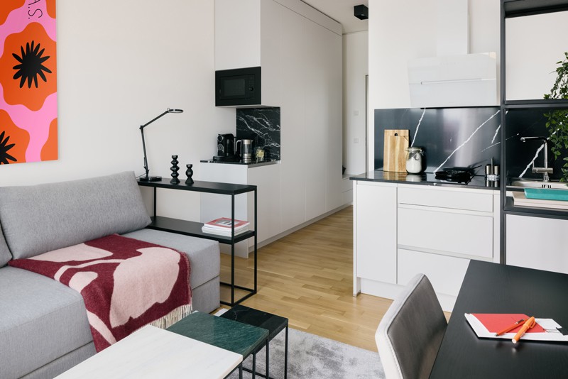 Business apartment in Berlin with gray sofa, coffee table, desk and modern kitchenette 