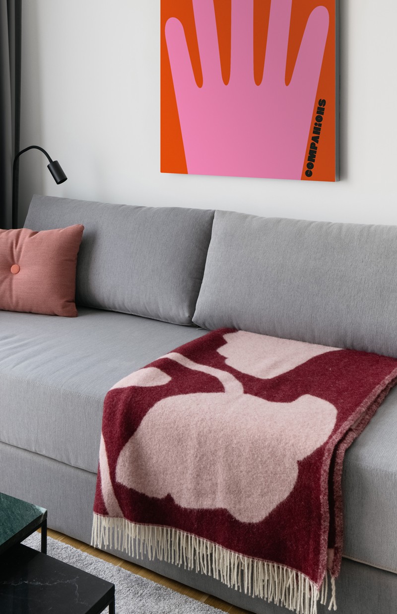 Modern gray sofa with dark red bedspread and orange and pink picture