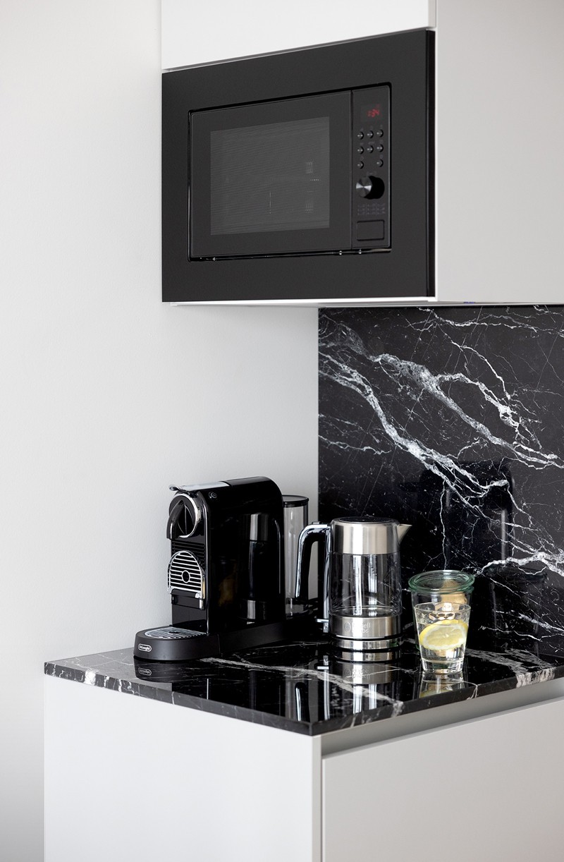 Schwarze Küchenzeile mit Mikrowelle und Espressomaschine 