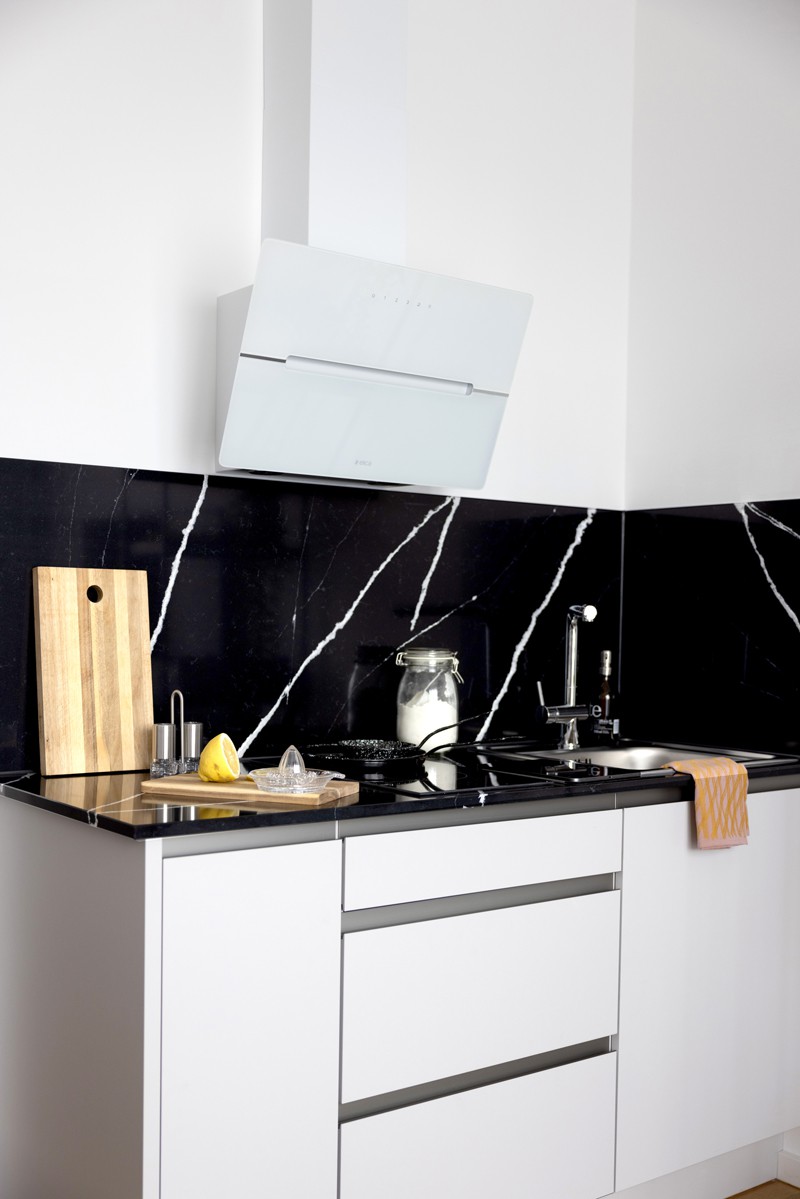 Weiße, edle Küchenzeile mit schwarzem Marmor als Arbeitsfläche