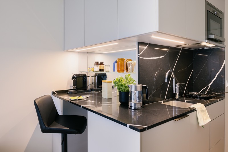 Küchenzeile mit schwarzem Marmor als Arbeitsfläche und frischem Basilikum