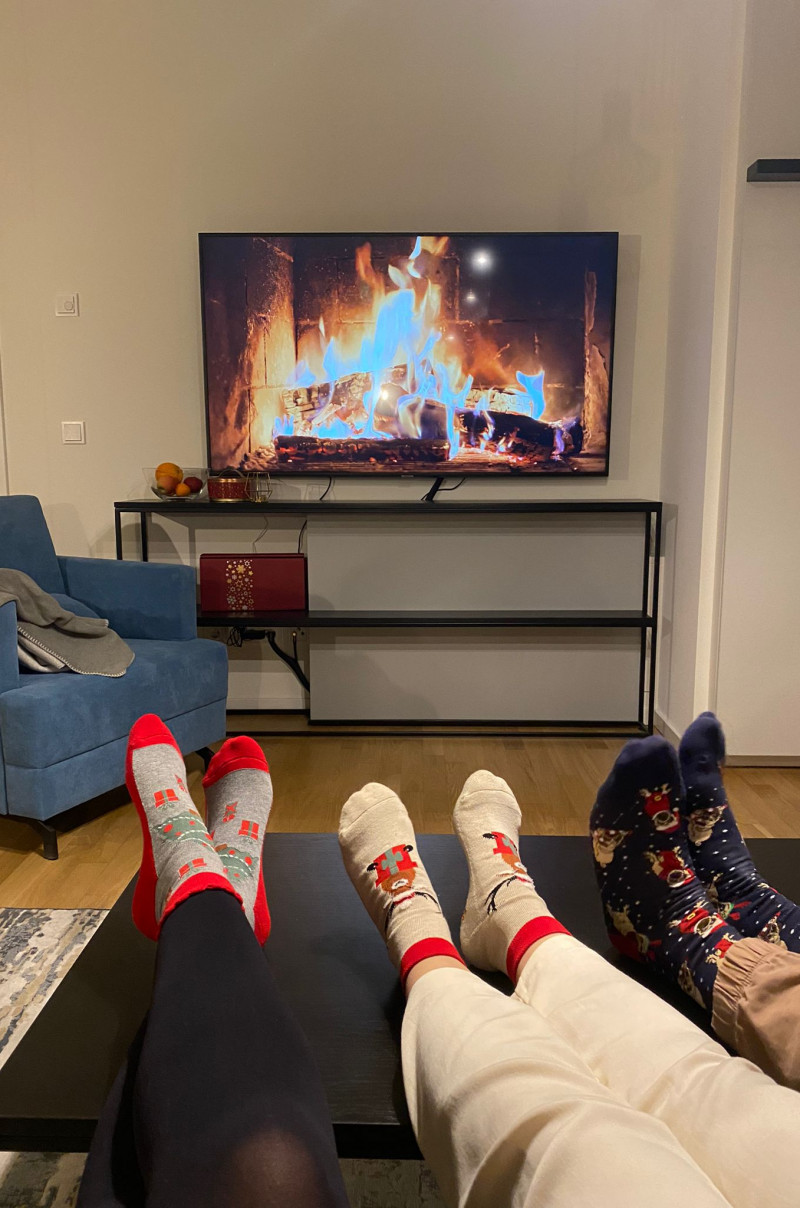 Fireplace played on a TV with feet in Christmas socks in front of it