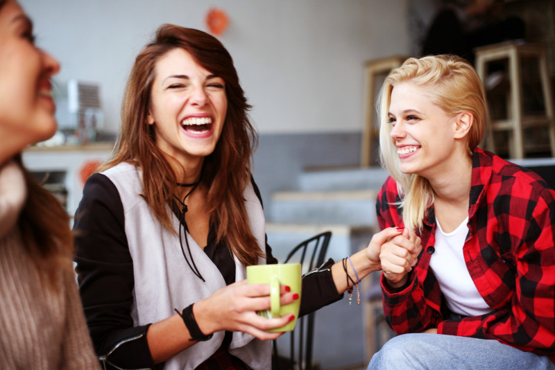 Drei lachende Frauen trinken gemeinsam Kaffee